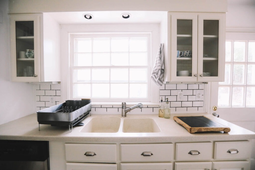 tiled kitchen with white units and a sink