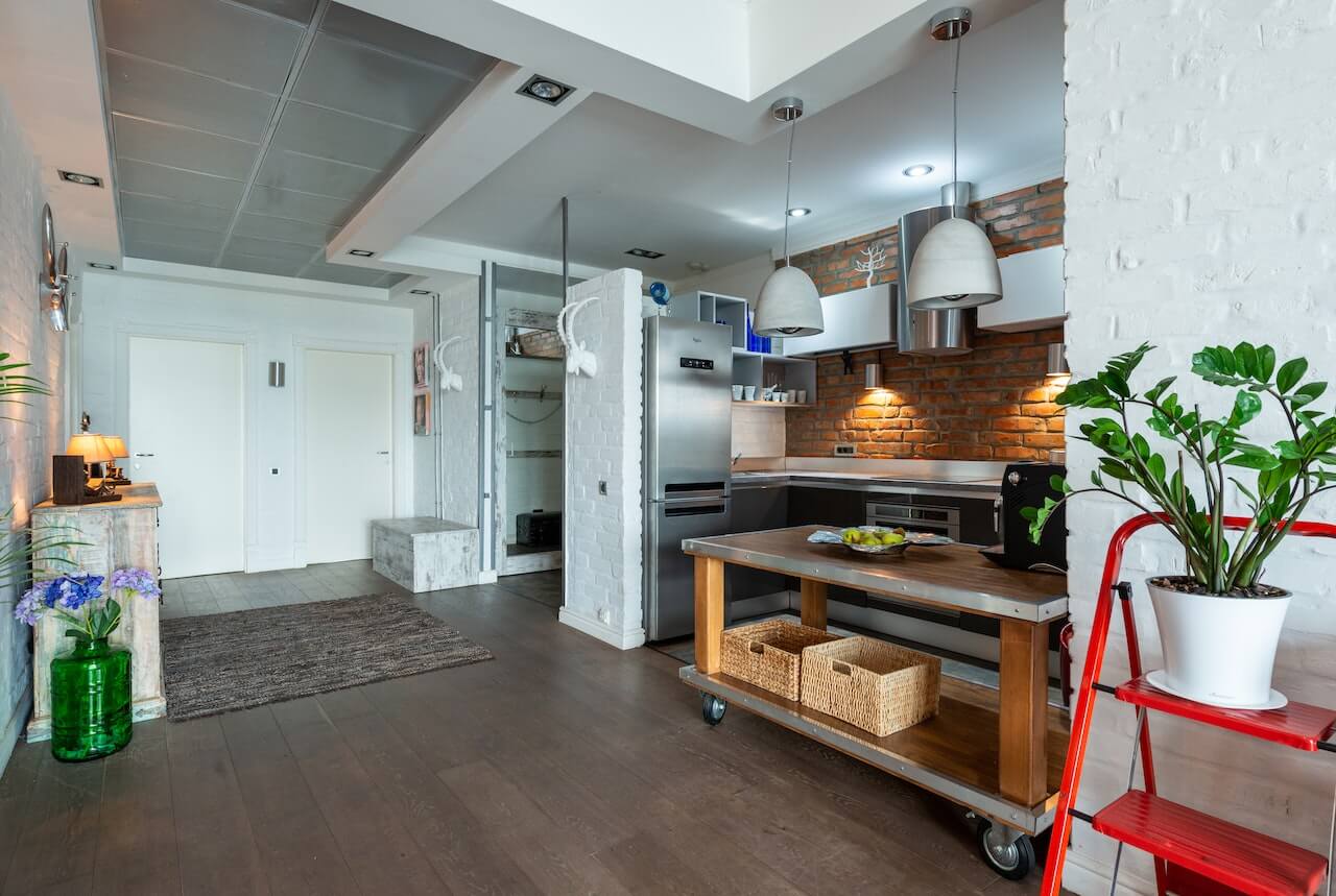 silver fridge with a silver countertop, featuring a wooden kitchen island and exposed brick backdrop